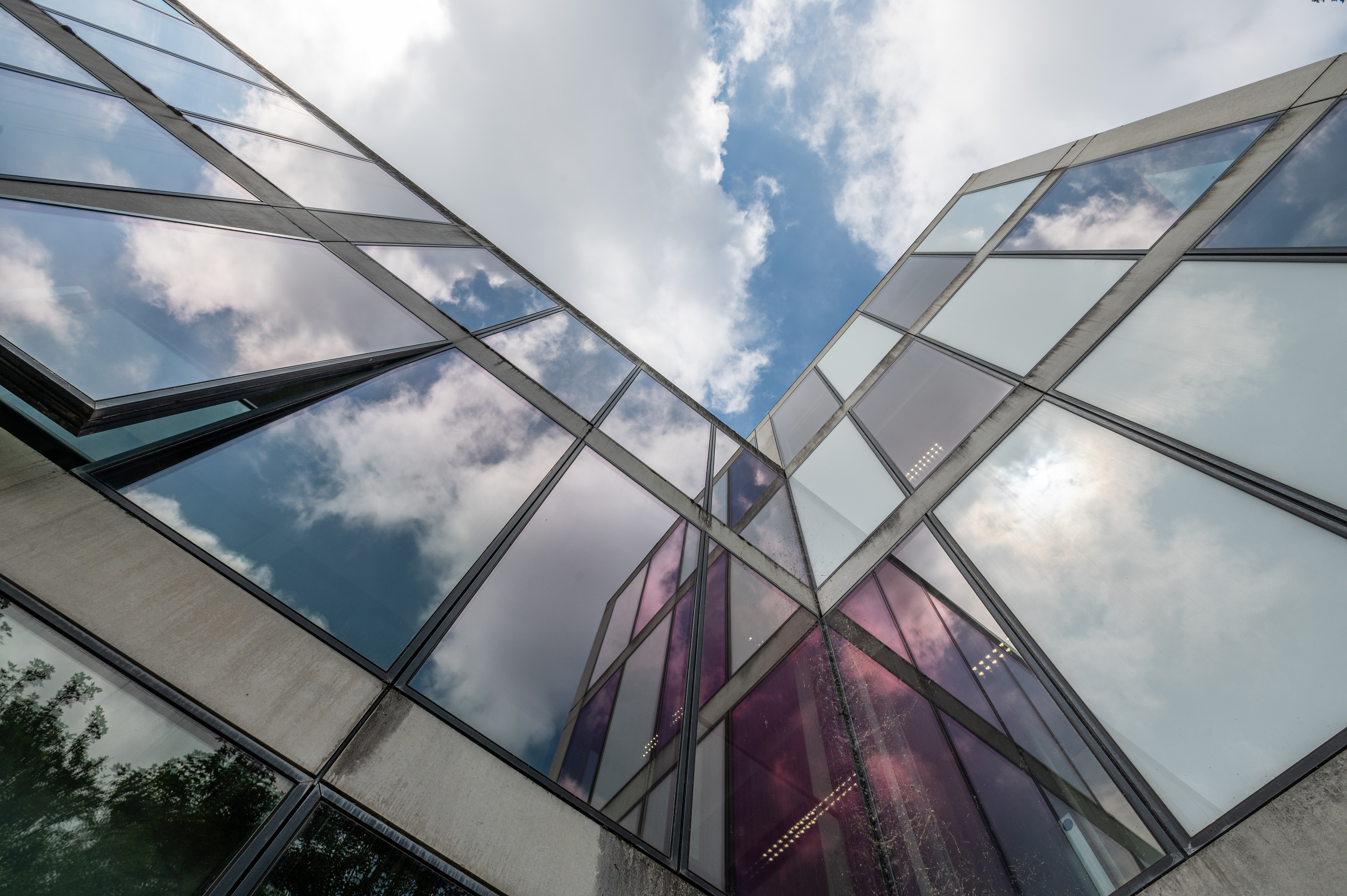 image of the glass sides of a building with a cloudy sky visible above