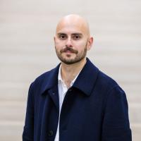 image of a man with a bald head wearing a dark jacket looking at the camera