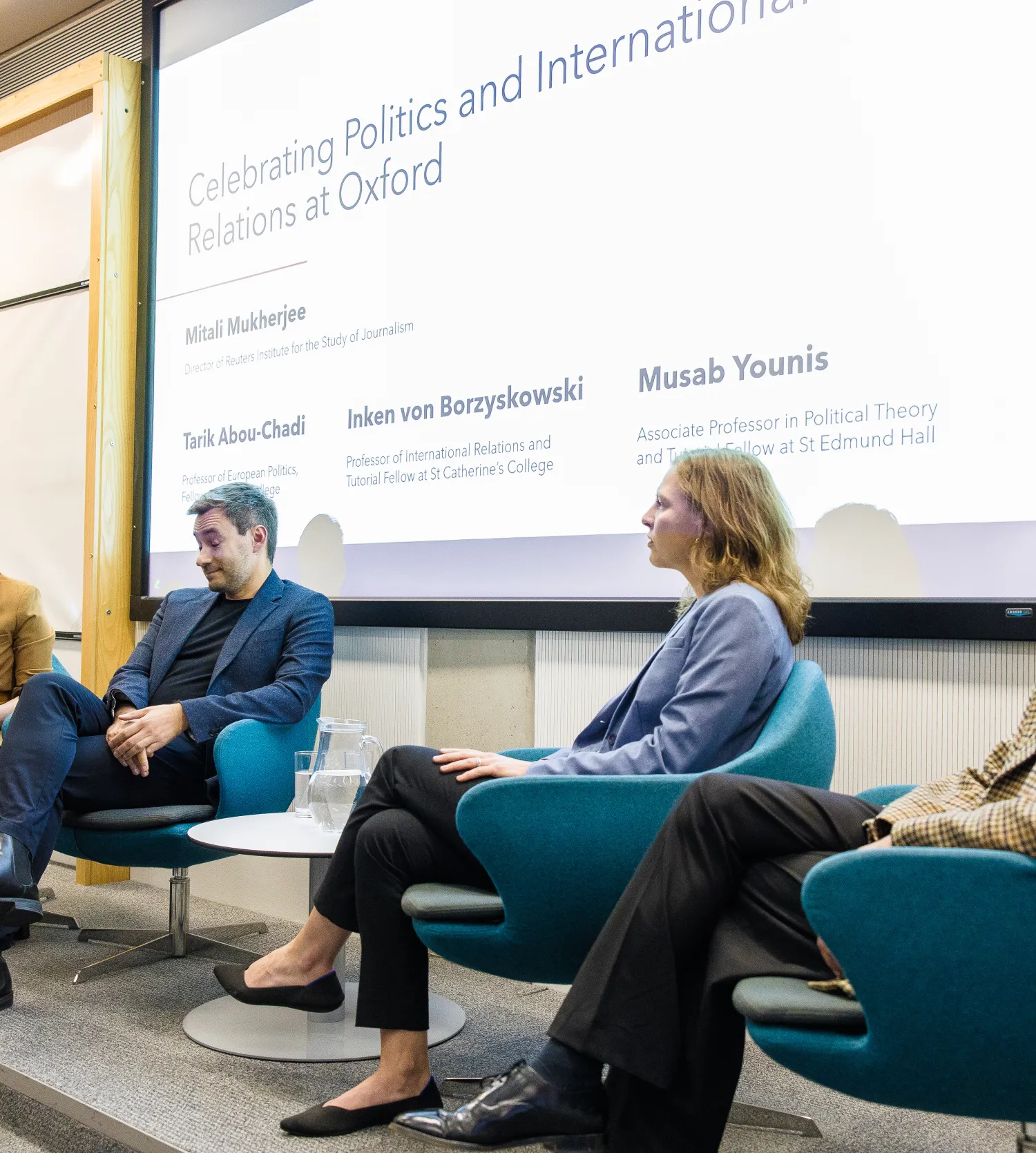 image of a panel of four people seated in front of a projector screen