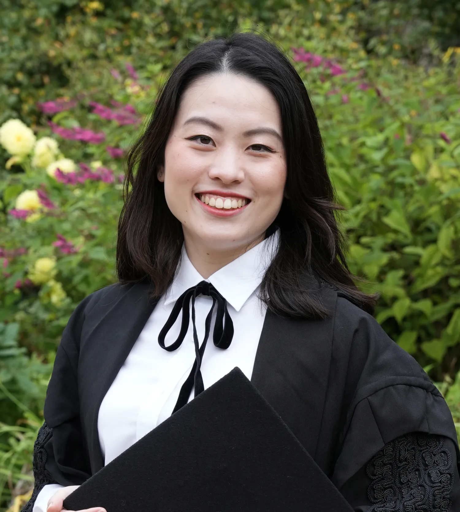 A woman wearing a black gown and white shirt smiling at the camera
