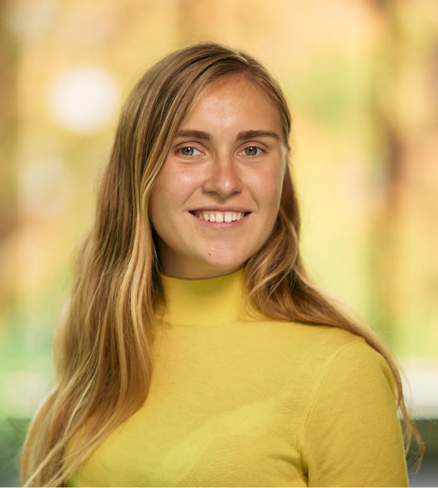 Image of a woman with long hair wearing a yellow top smiling at the camera