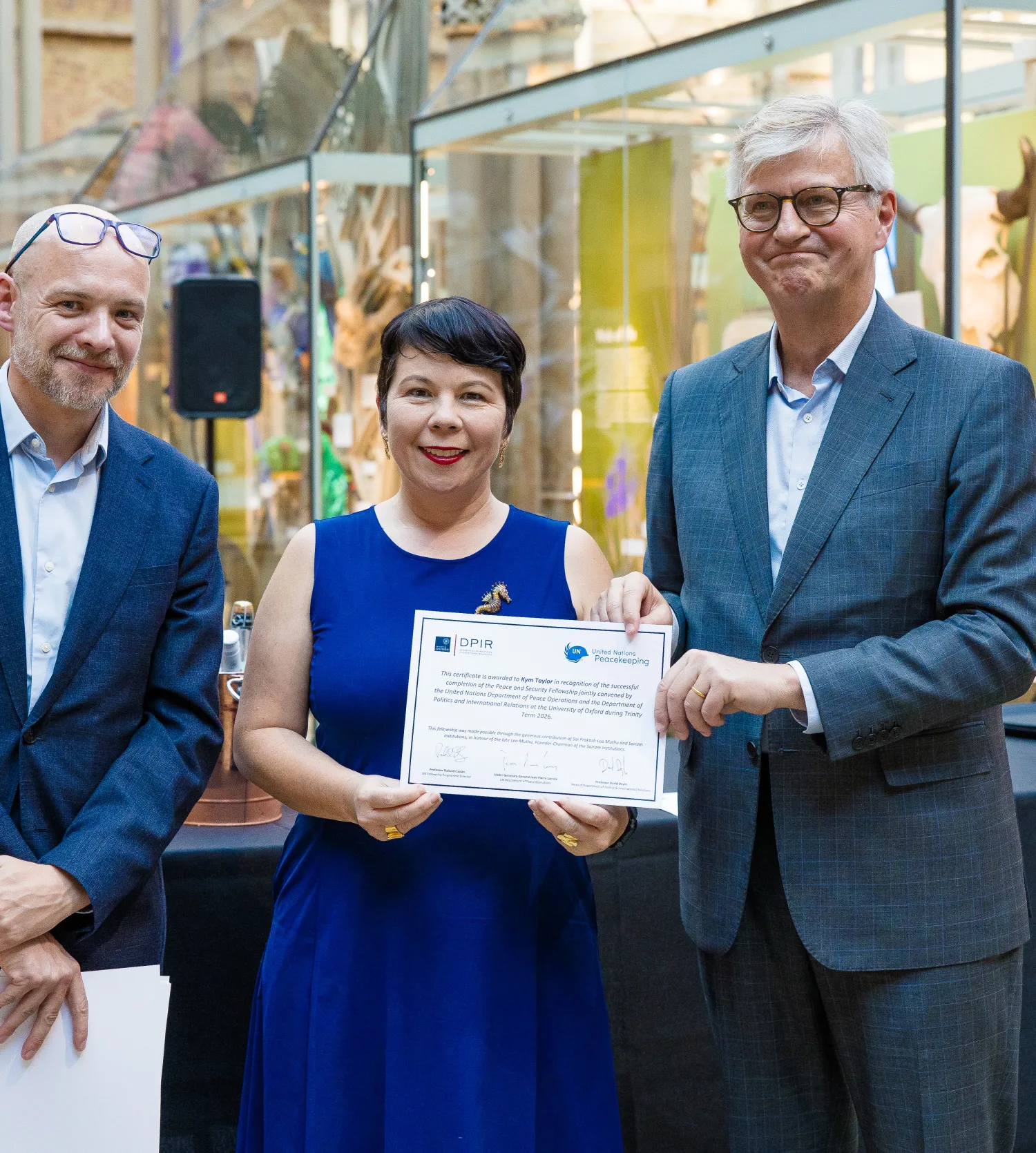 image of two men presenting a certificate to a woman