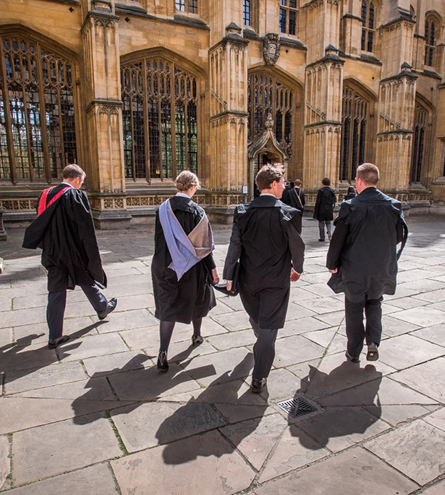 image of four students in gowns in front of the Divinity School in Oxford
