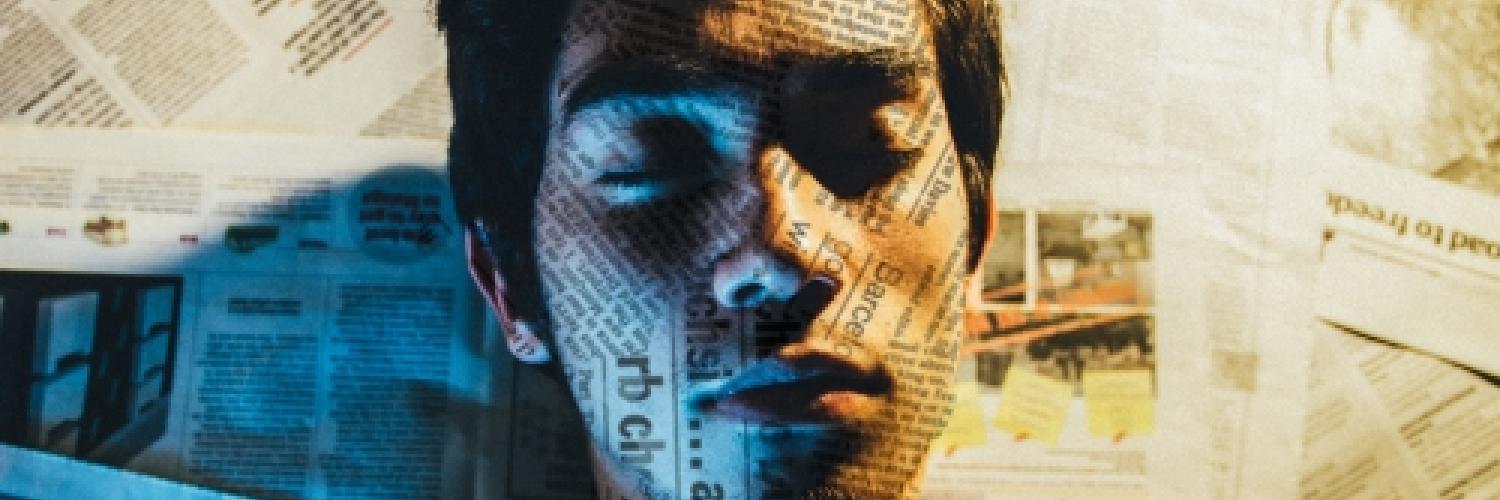 Image of a man lying down on newspaper pages