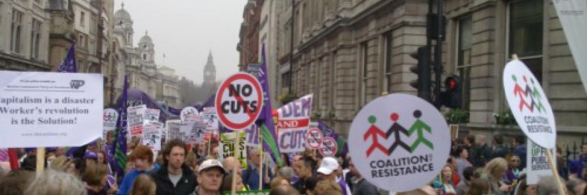 Crowd holding placards including one reading 'no cuts'