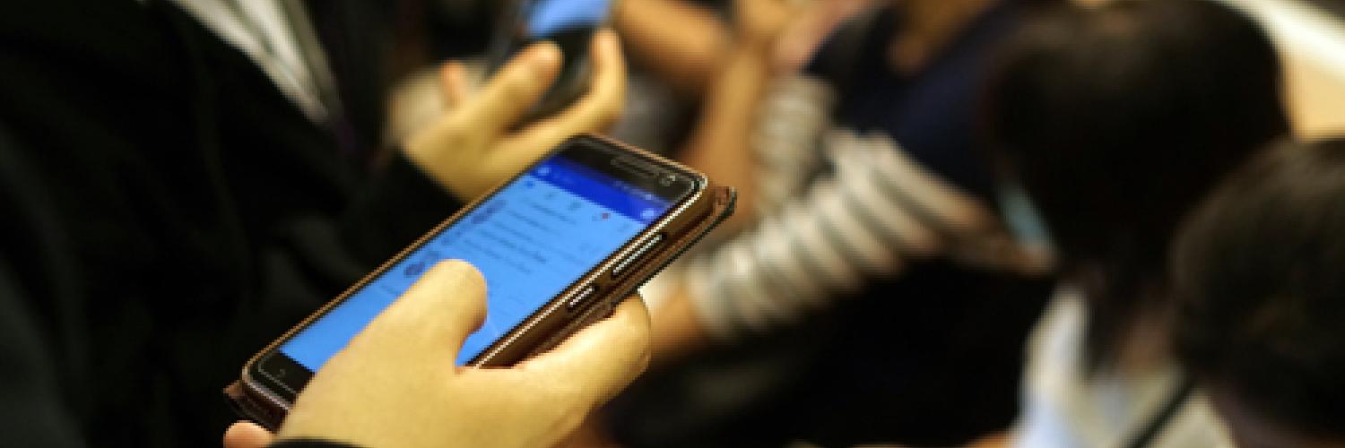 An image of someone holding a mobile phone on a train.