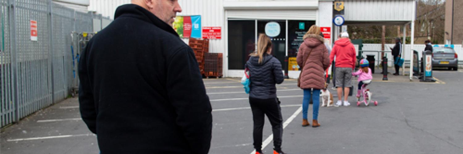 People queuing outside a supermarket. 