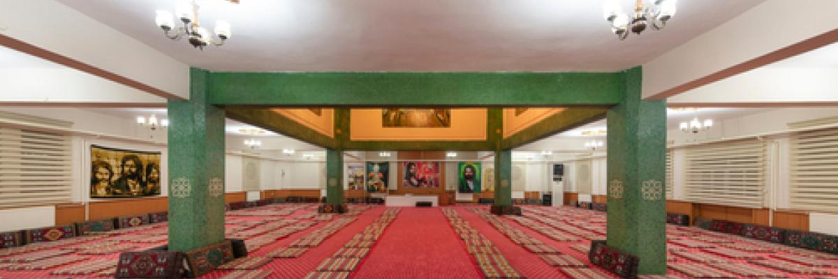 Image of a place of worship with prayer mats on the floor. 