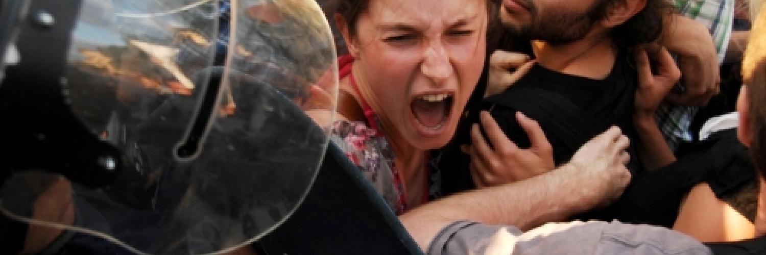 A crowd of people with riot police in the foreground