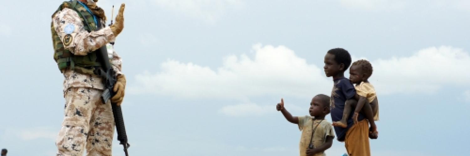 A UN soldier waving to a group of children