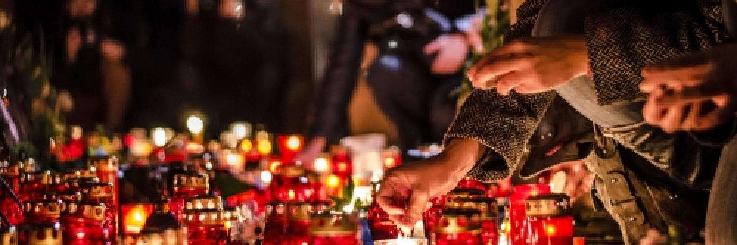 Image of a number of candles on the floor and people lighting them