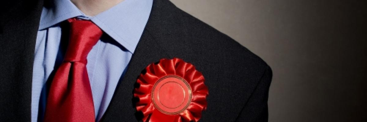 An image of a man wearing a red tie and rosette