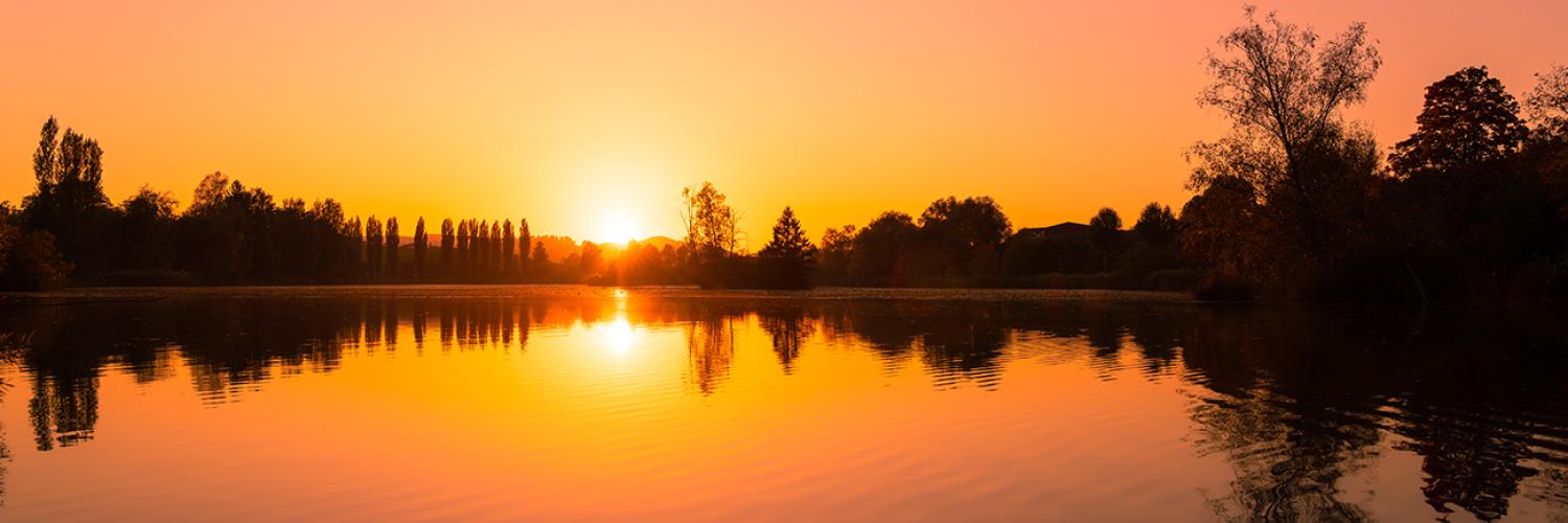 A scenic view of the sun reflecting on a calm sea during a beautiful sunset