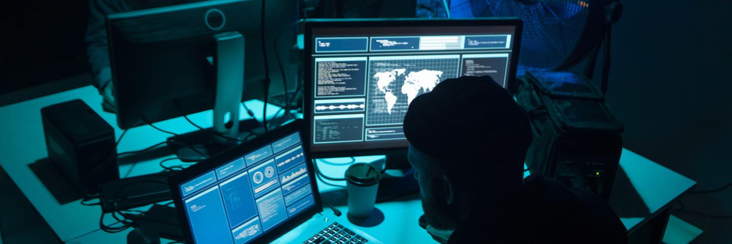 Two man sat in front of computers in  darkened room