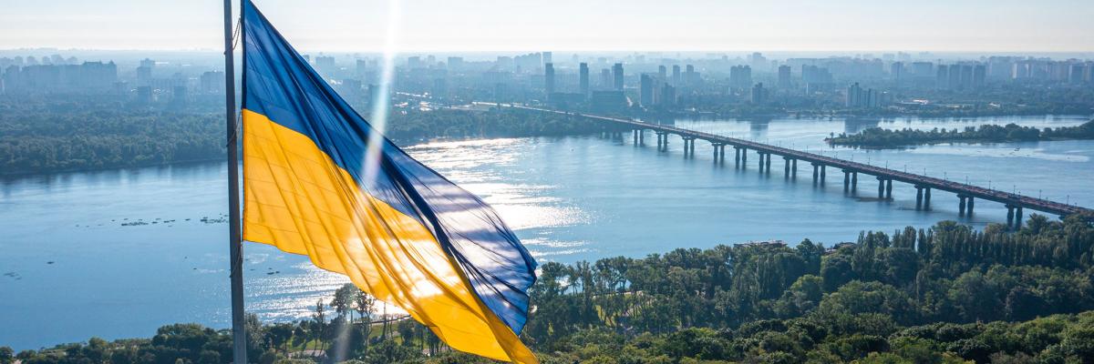 Image of the Ukrainian flag with a river and sunny sky behind