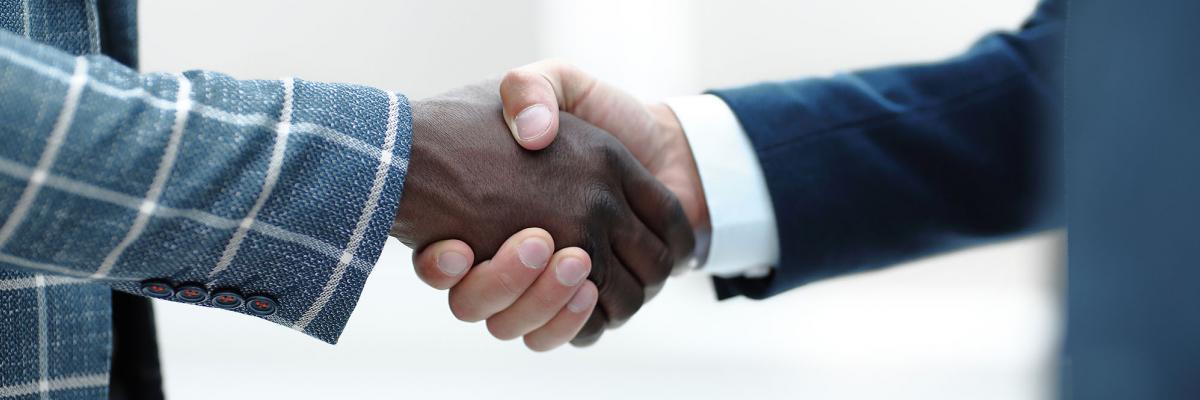 Two business men shaking hands, with different skin colours