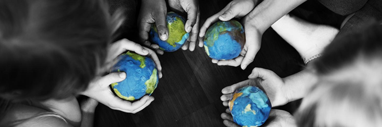 Group of diverse kids hands holding cupping globe balls together