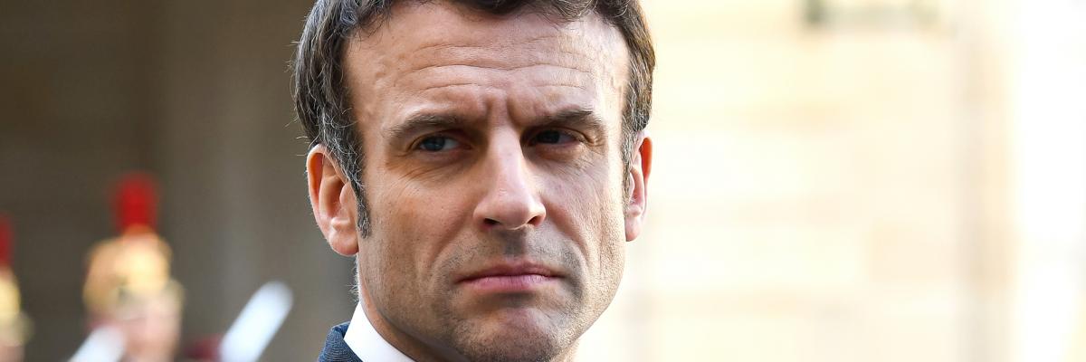 Portrait image of French President Emmanuel Macron in a suit standing outside