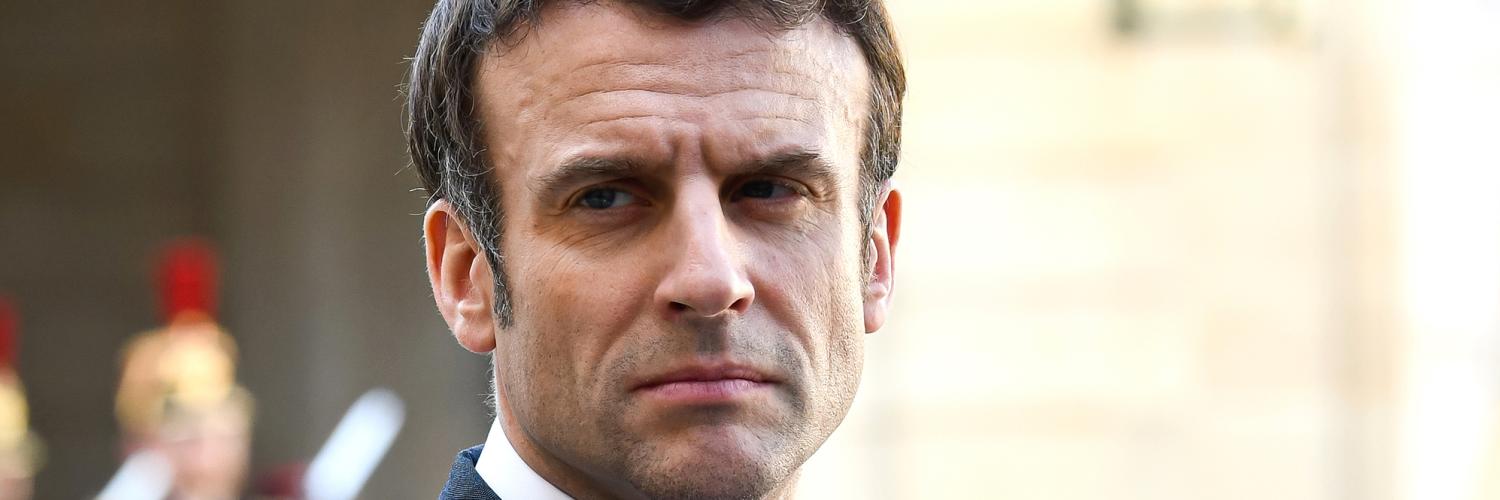 Portrait image of French President Emmanuel Macron in a suit standing outside