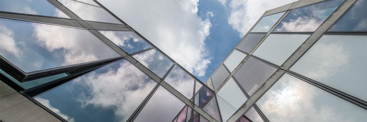 Upwards shot of a building's windows against a blue cloudy sky