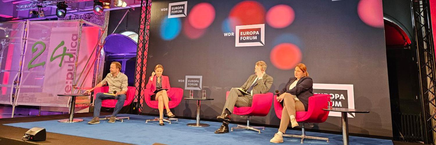 Image of a panel of people sat in chairs on a stage