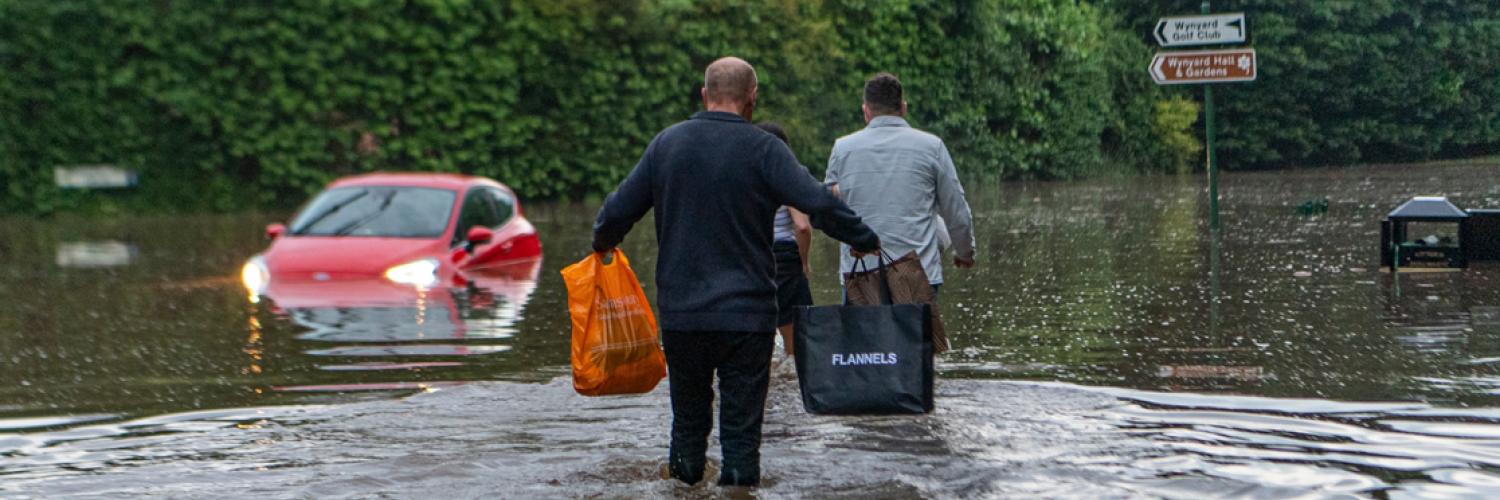 Two people walking through flooded street