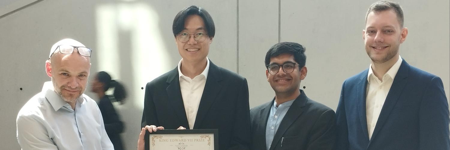 image of four men looking at the camera holding a prize certificate