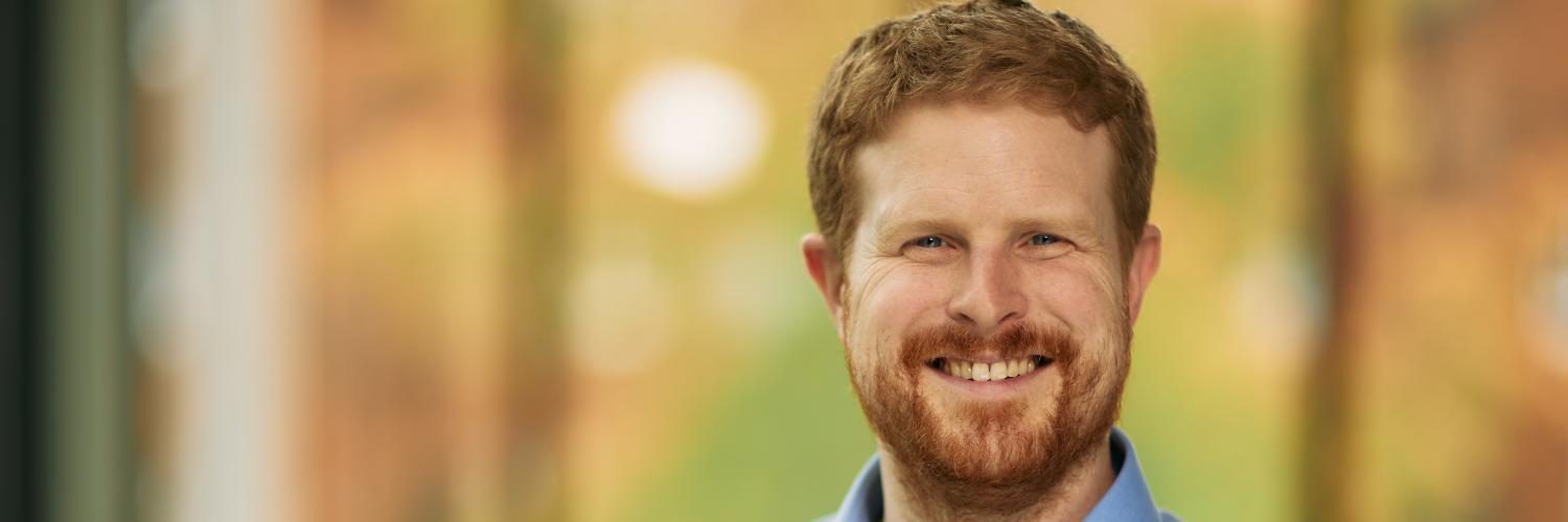 headshot of a bearded man smiling at the camera