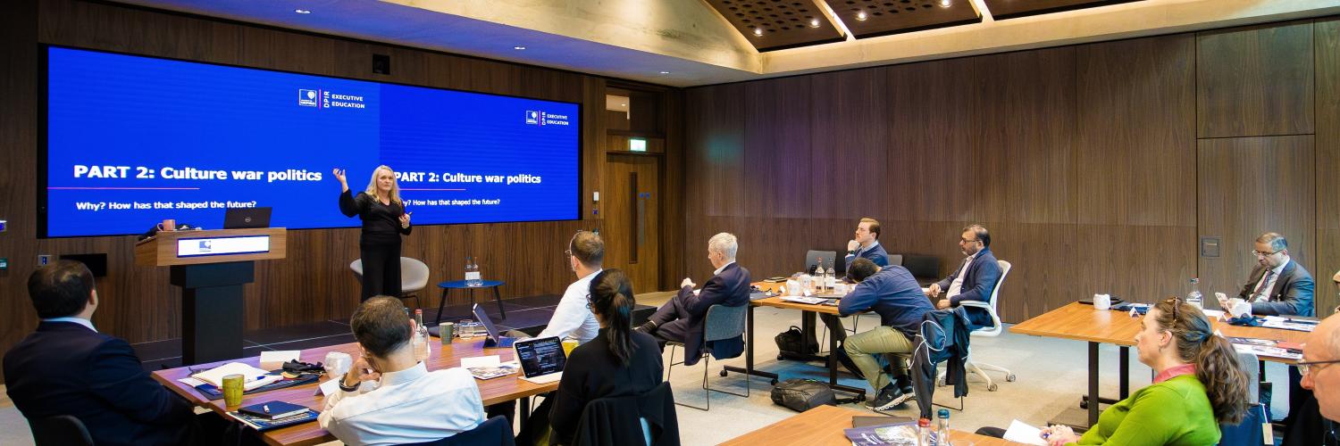 Image of people in a room looking at a presentation on a screen
