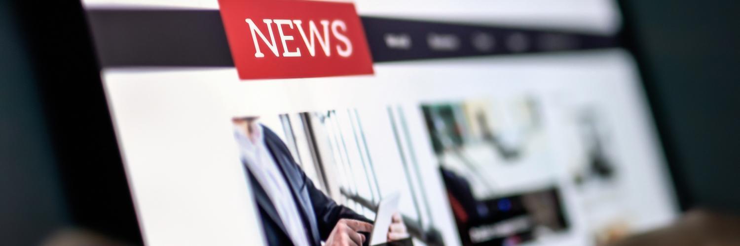 Image of hands holding a tablet screen with writing on including the word ‘NEWS’