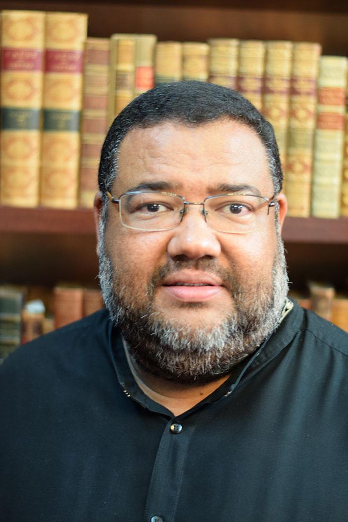 Athol Williams profile photograph, with old library books in the background