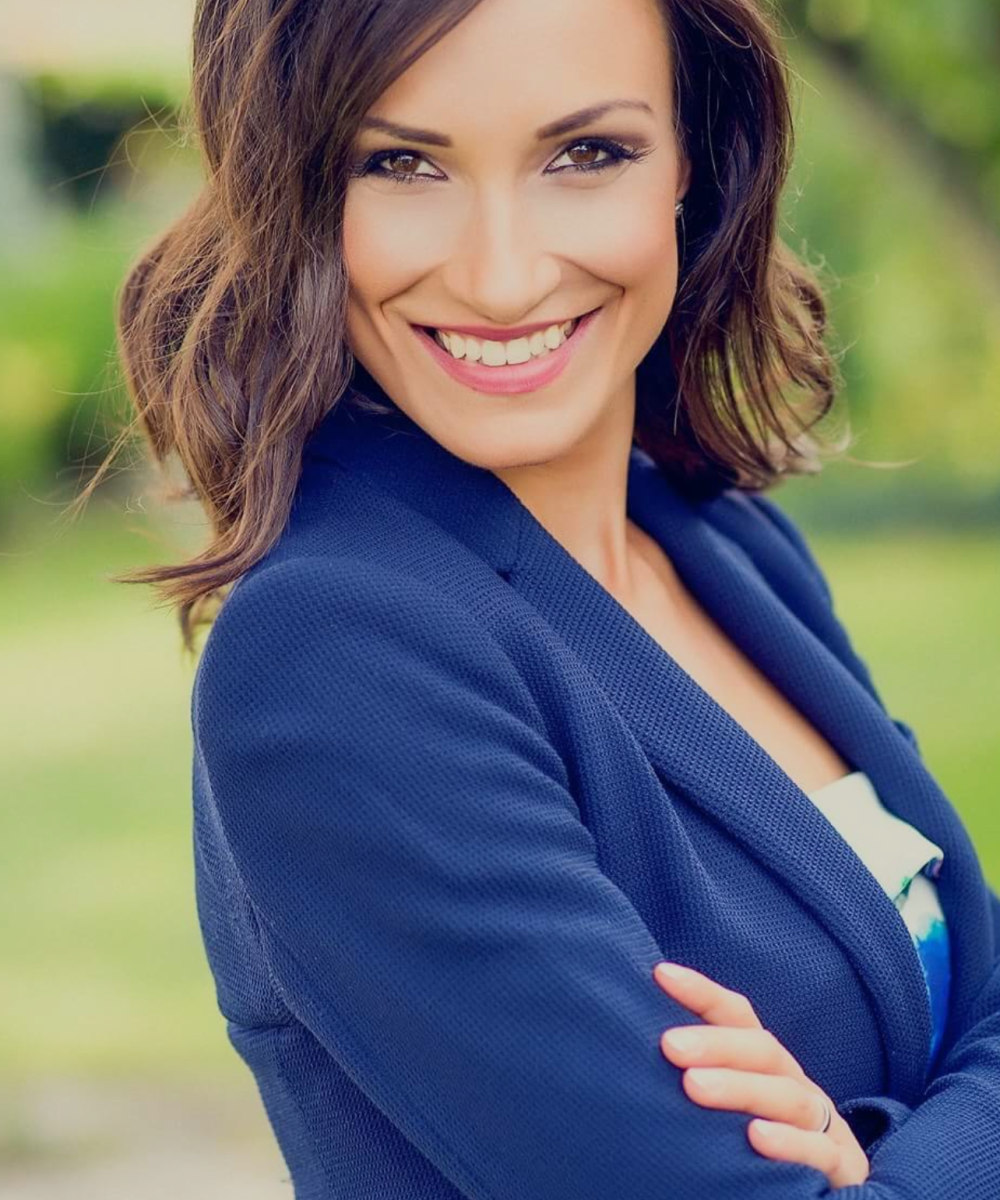 Image of a woman with long hair wearing a blue suit smiling at camera