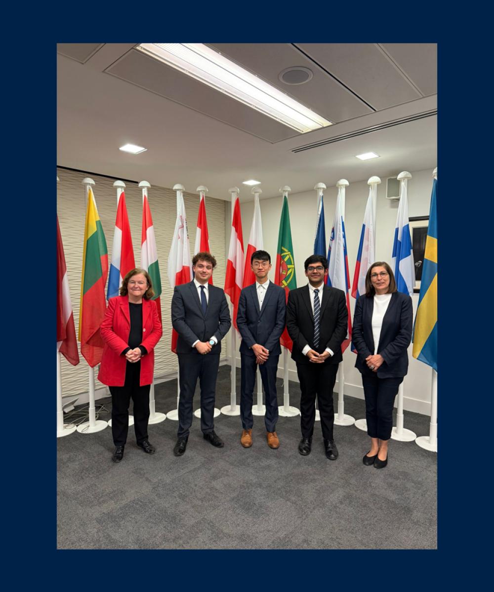 Image of five people in suits stood in front of a number of world flags