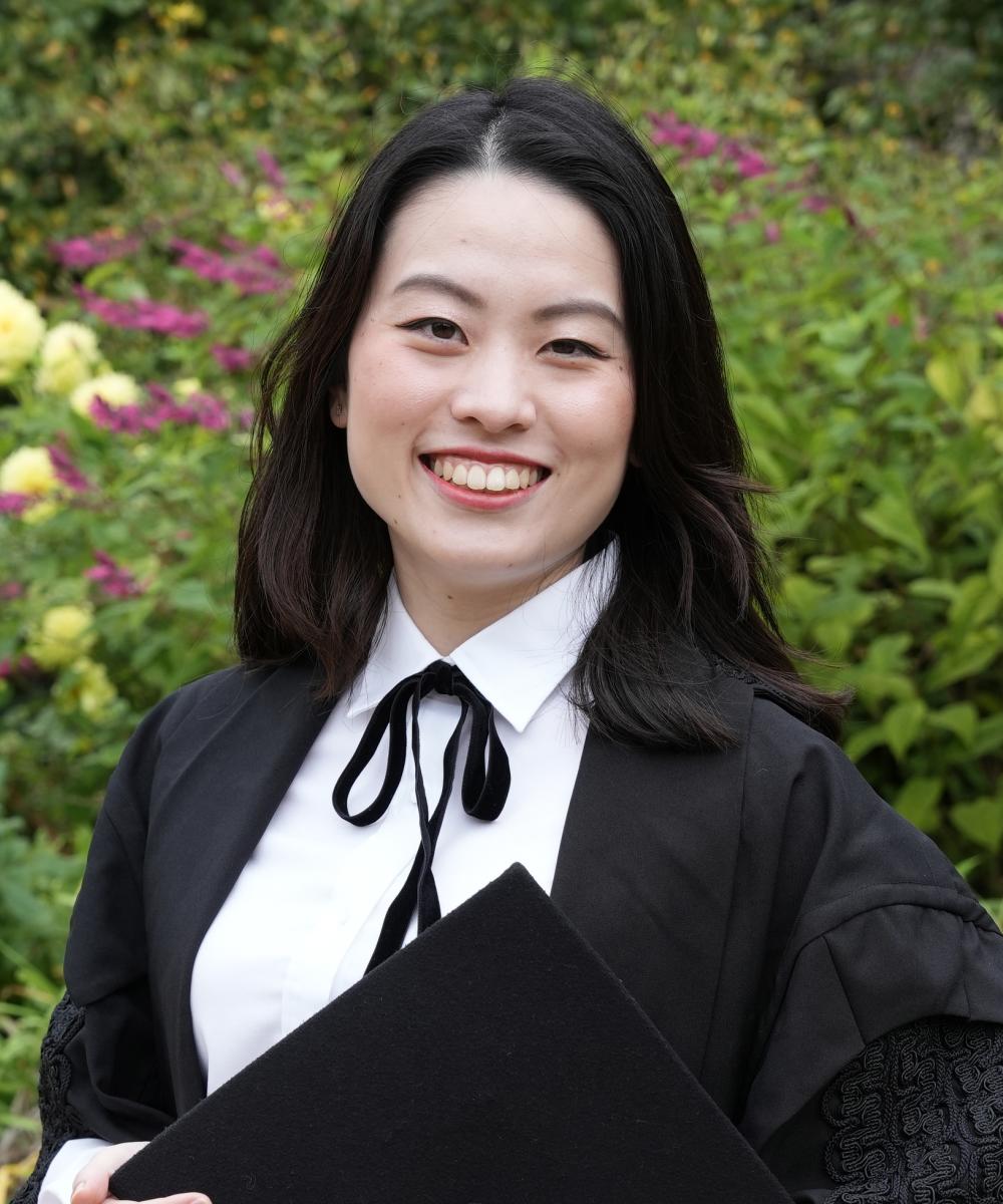 A woman wearing a black gown and white shirt smiling at the camera
