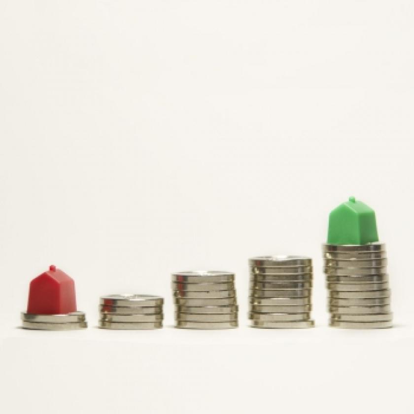 Five piles of coins with red and green Monopoly houses on two of the piles