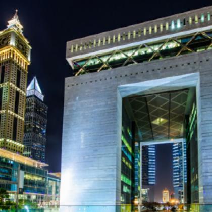 Picture of an arch lit up in Dubai with tall buildings in the background