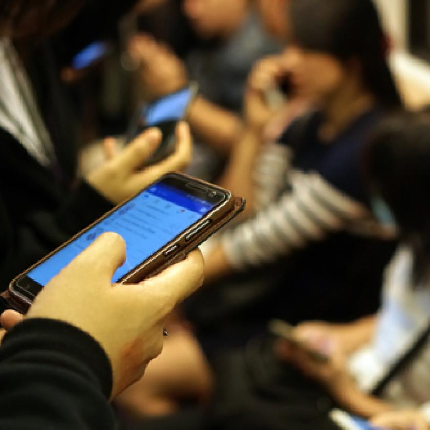 An image of someone holding a mobile phone on a train.