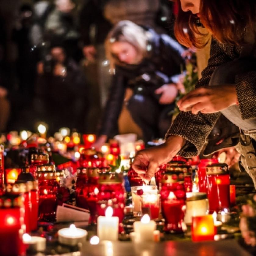 Image of a number of candles on the floor and people lighting them
