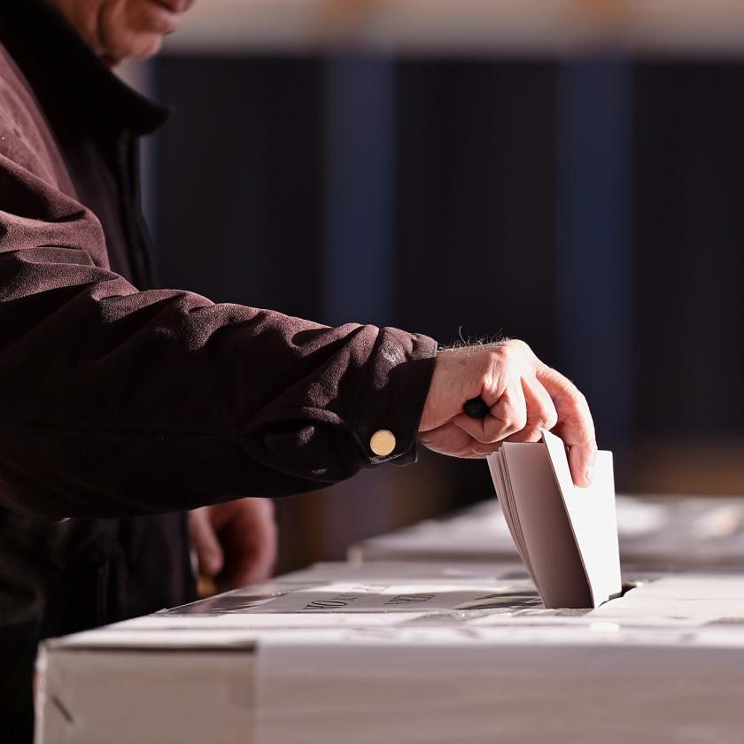 Hand of a person casting a vote into the ballot box during elections