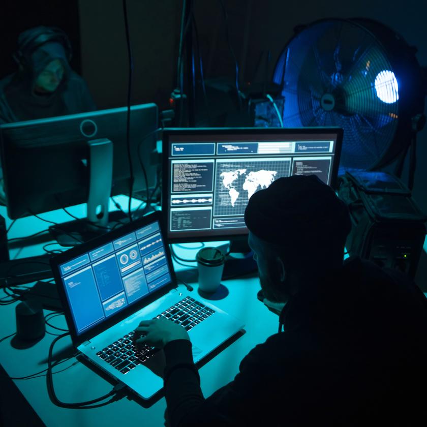 Two man sat in front of computers in  darkened room