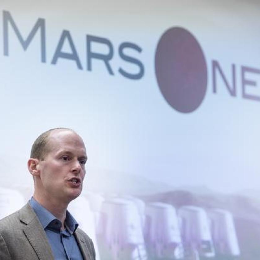 A man speaking in front of a screen