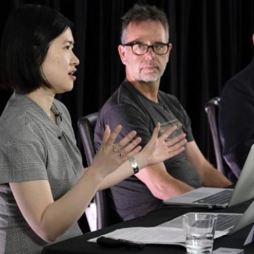 Several people sat at a desk in front of laptop screens