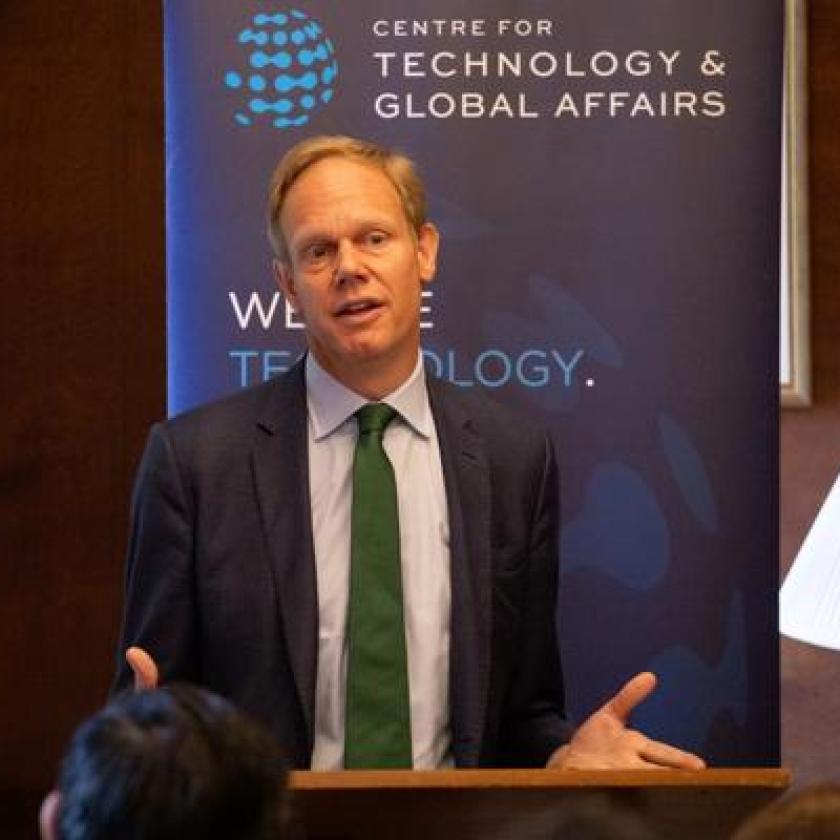 A man in front of a lectern addressing an audience