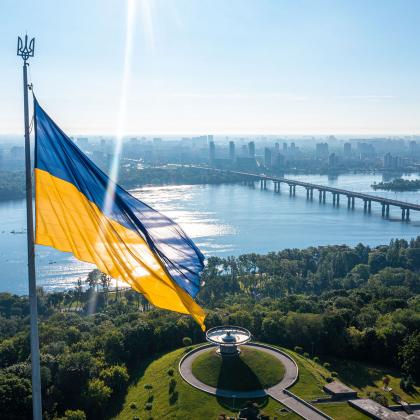 Image of the Ukrainian flag with a river and sunny sky behind