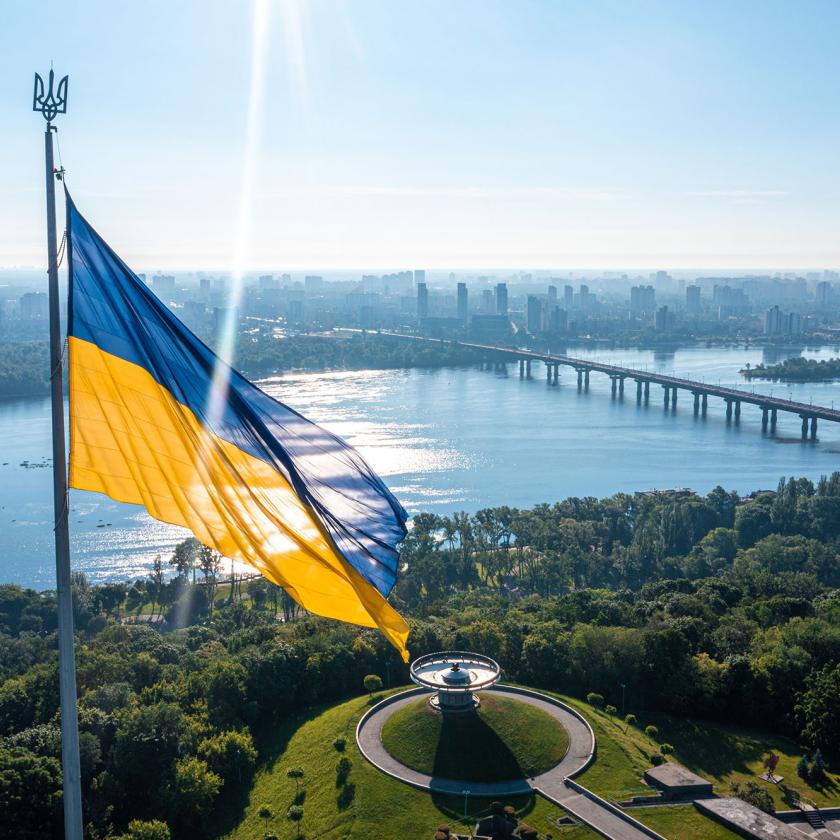 Image of the Ukrainian flag with a river and sunny sky behind