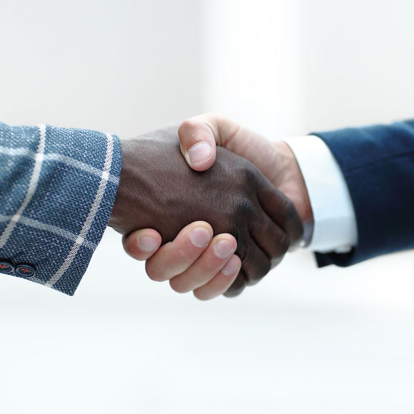 Two business men shaking hands, with different skin colours