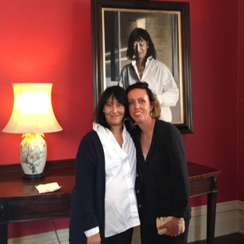 A couple of women posing for a picture in front of a painting