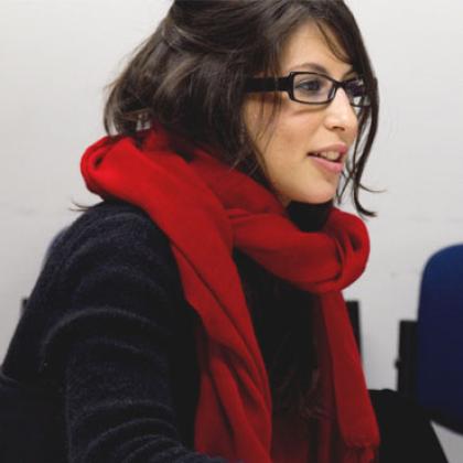An image of a woman wearing glasses sat sideways working at a desk