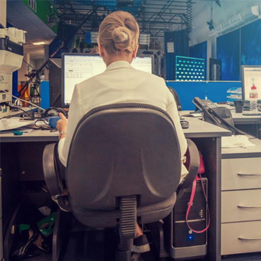 Image of two women facing away from the camera working at computer screens in an office