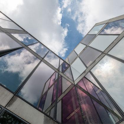 Upwards shot of a building's windows against a blue cloudy sky